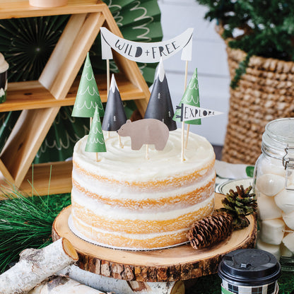 8 individual adventure./ happy camper cake topper. 3 x green mountain trees, 2 black and white mountain tops, 1 x Wild and Free mini cake topper banner, 1 x bear, 1 x explore pennant flag.